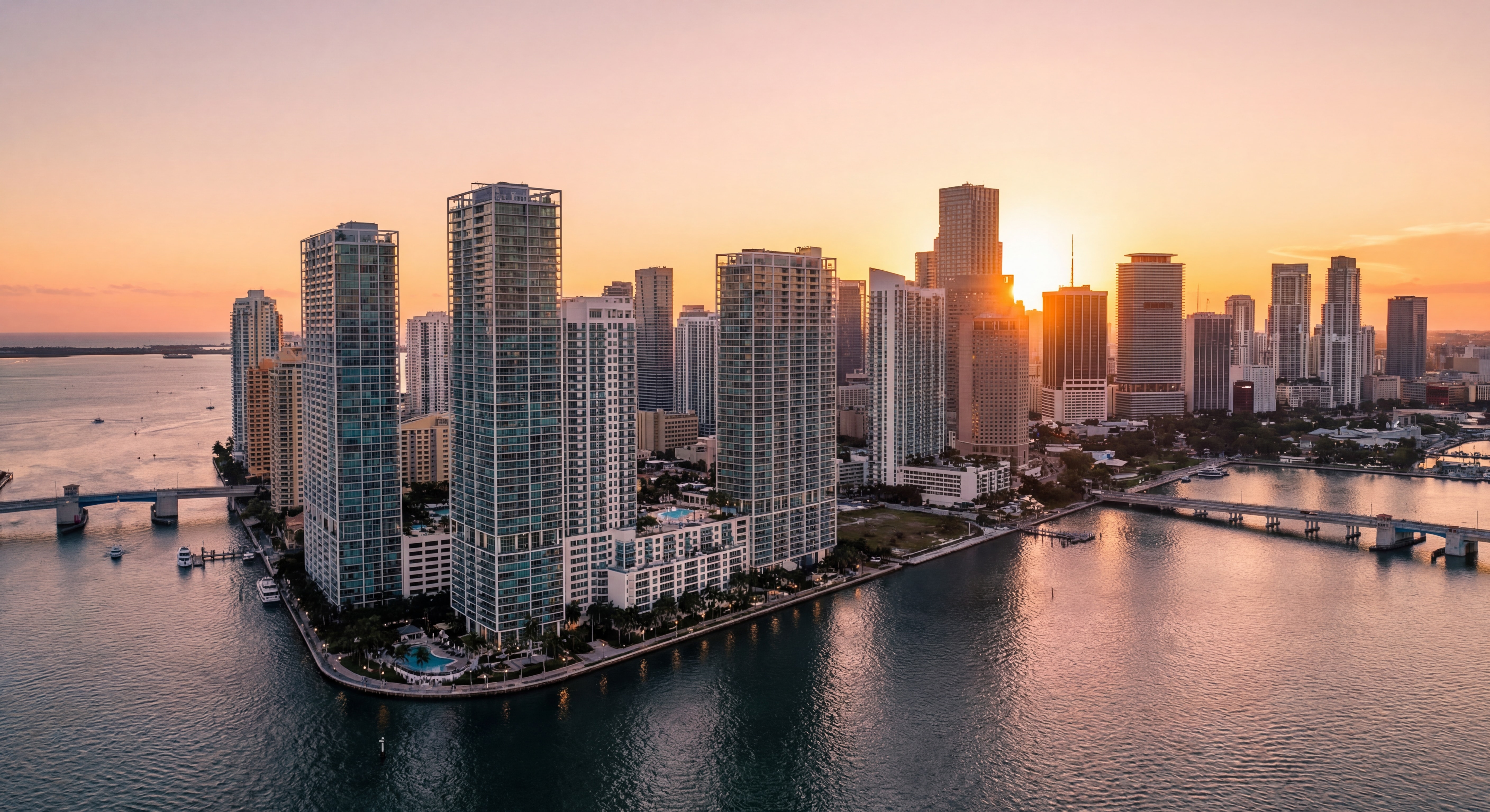 Aerial view of Miami's Brickell skyline with luxury waterfront towers reflecting in Biscayne Bay at sunset