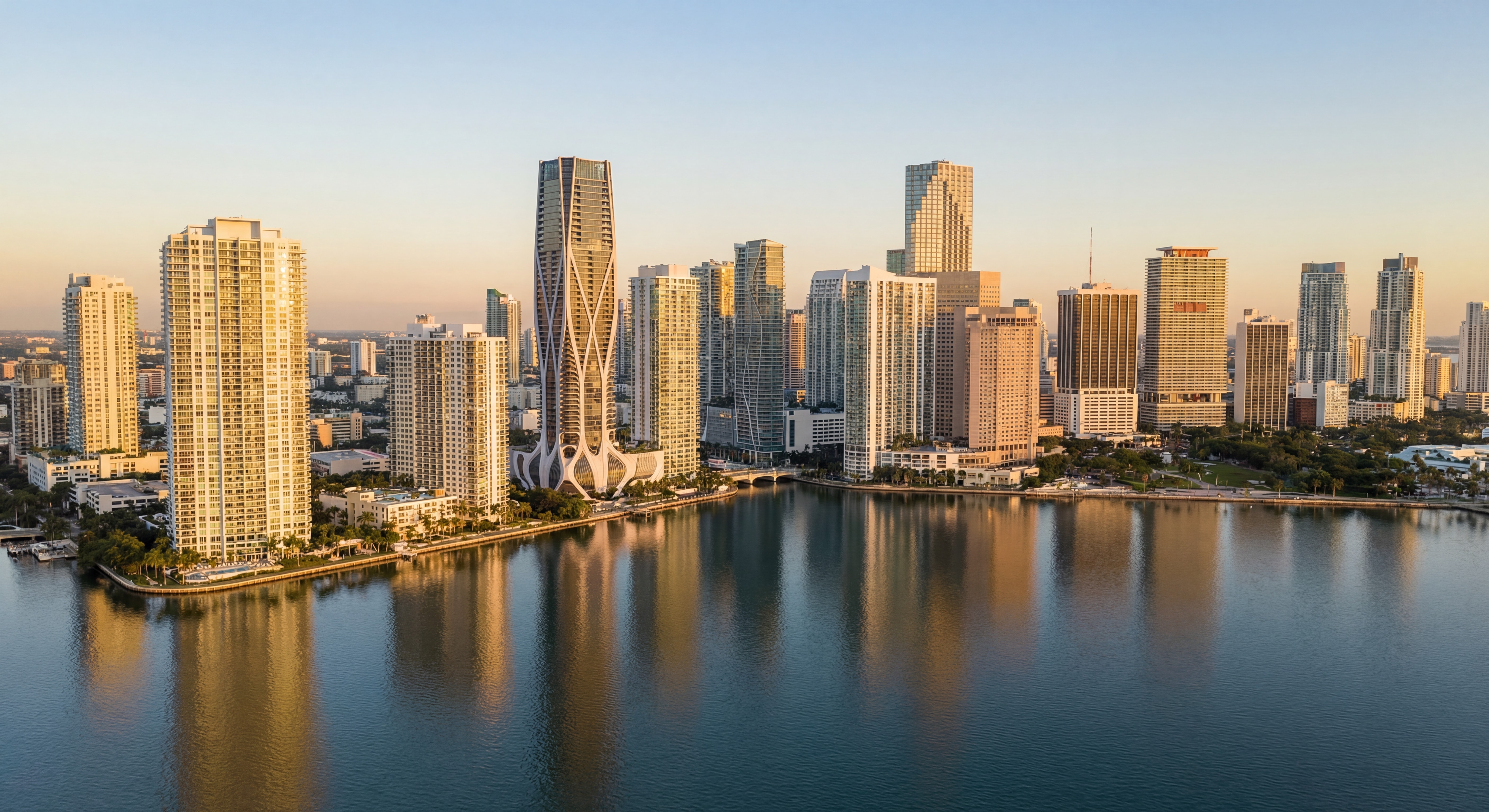 Miami skyline at golden hour with luxury high-rise towers reflecting on Biscayne Bay, aerial drone view