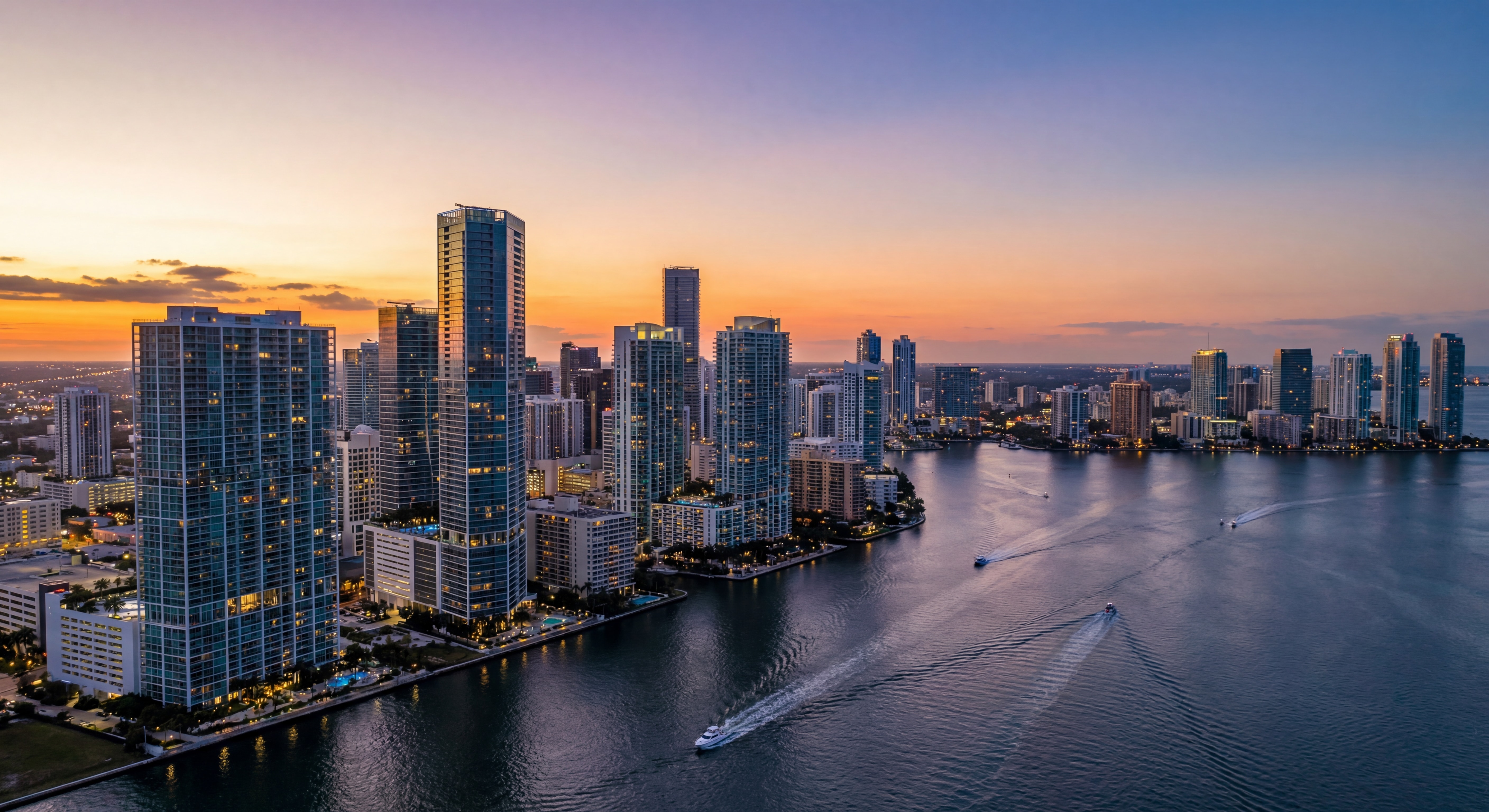 Aerial drone view of Miami's Brickell skyline at sunset with luxury waterfront high-rise towers reflecting on Biscayne Bay