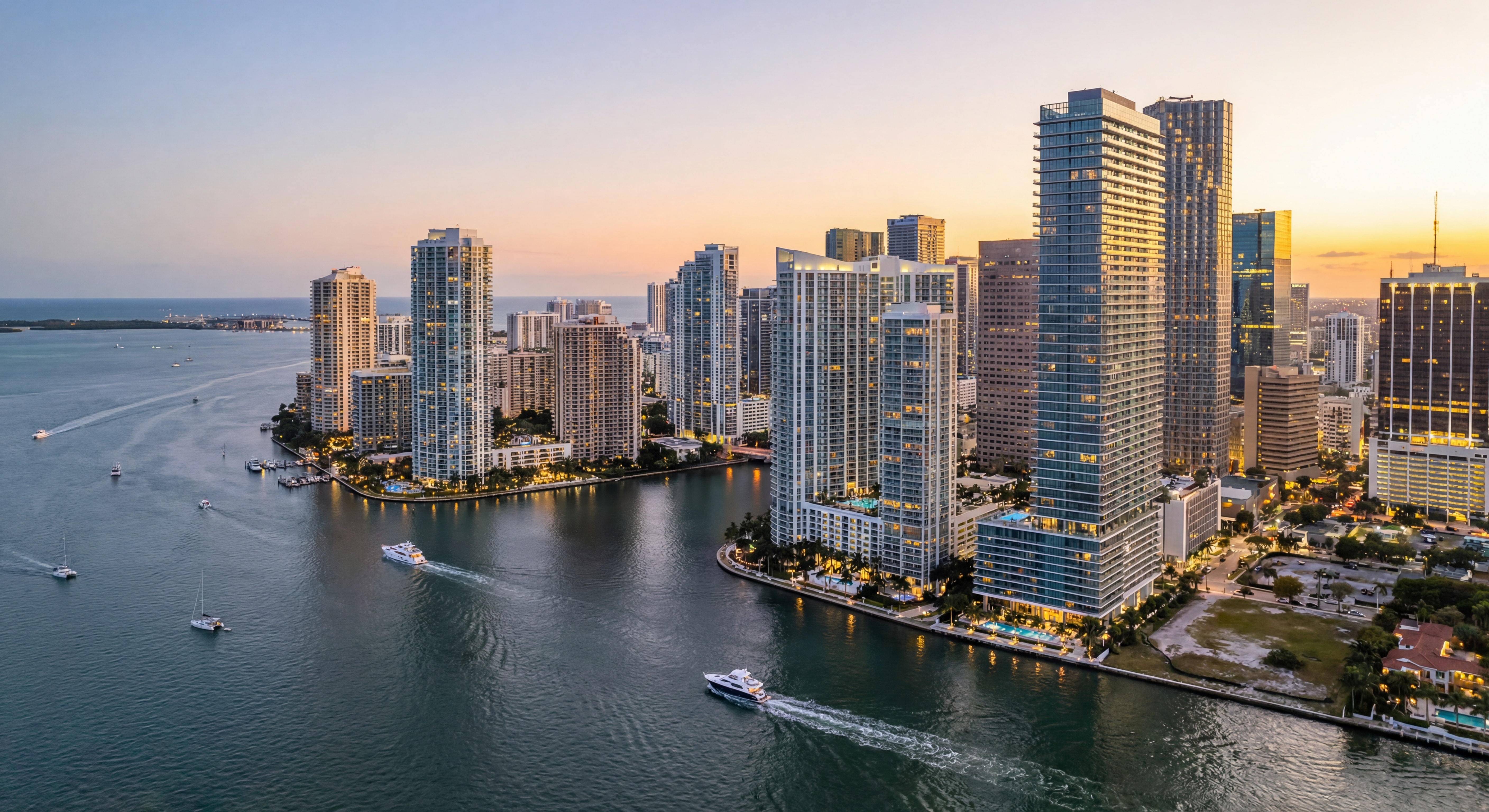 Aerial view of Miami's Brickell skyline at golden hour with luxury waterfront high-rise towers reflecting on Biscayne Bay