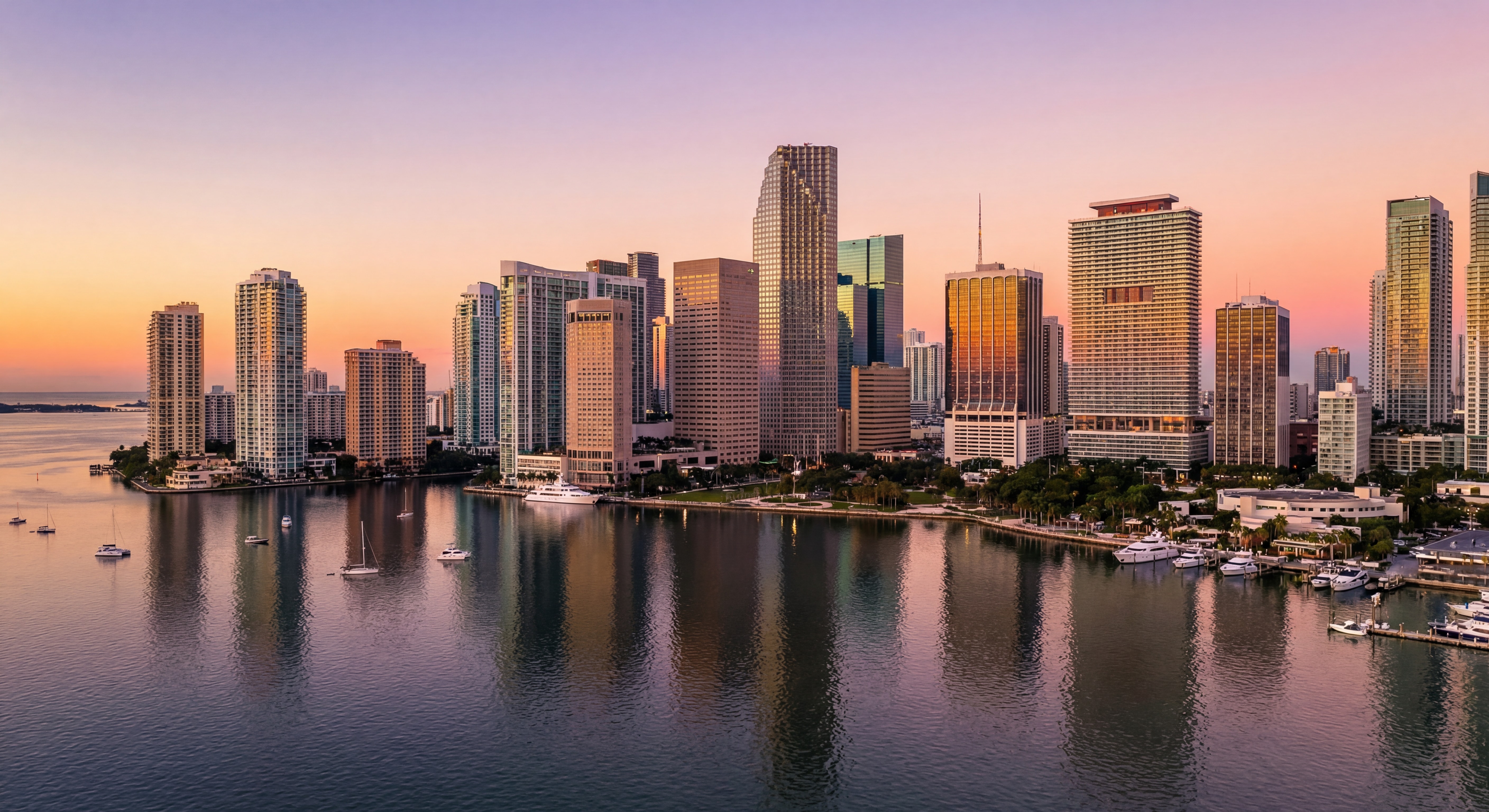 Aerial view of Miami's Brickell skyline at sunset with luxury high-rise towers reflecting on Biscayne Bay