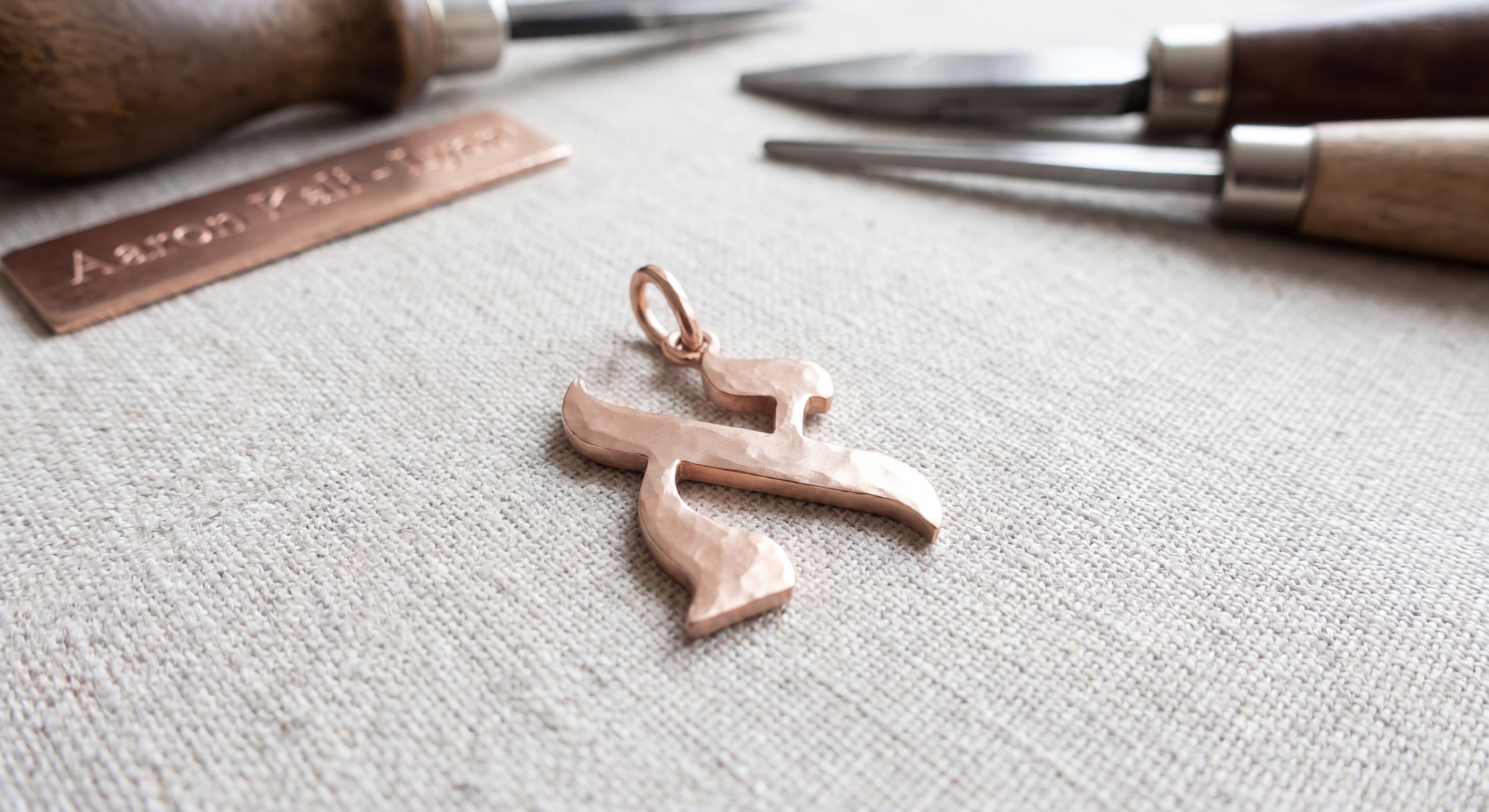 Détail d'un pendentif lettre hébraïque Kalligraphe en or rose 18 carats, fabriqué à la main dans un atelier lyonnais, bijou artisanal Aaron Kali sur-mesure