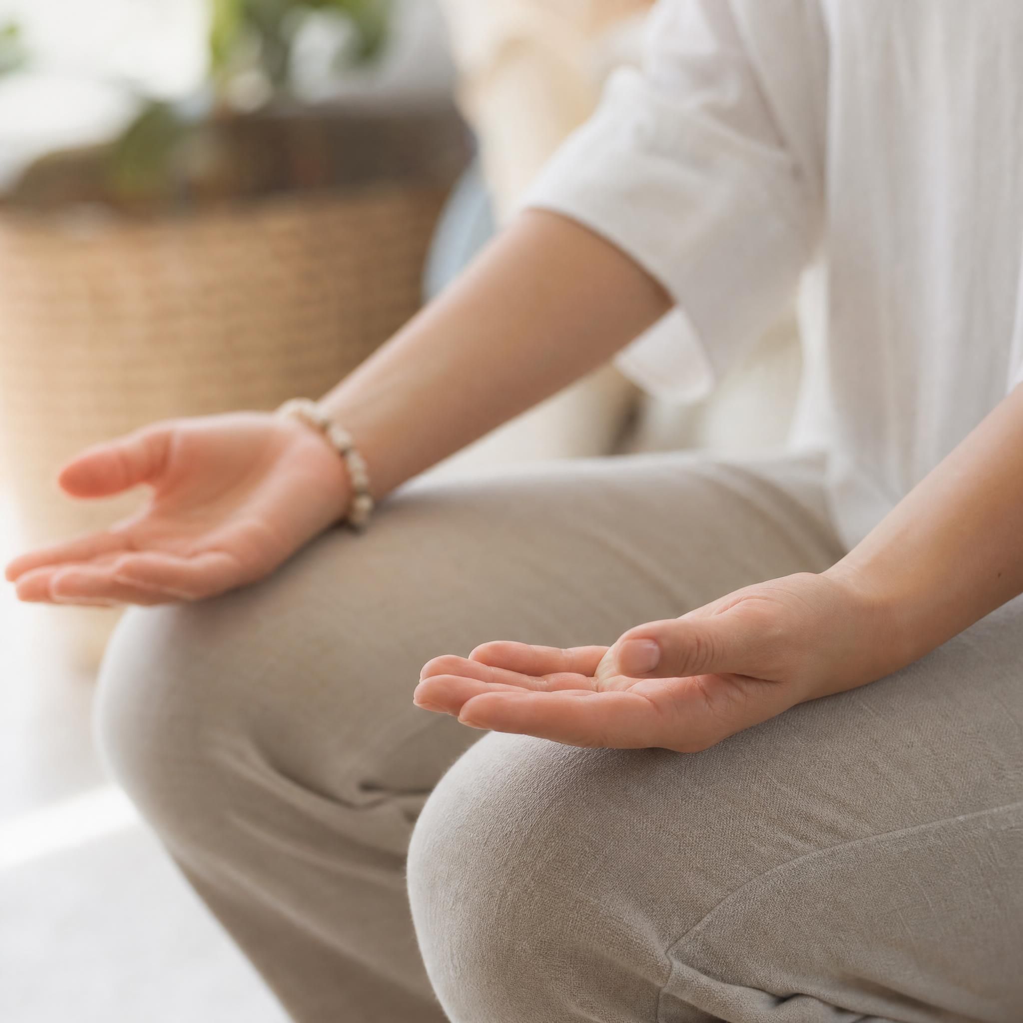 Gros plan sur les mains d'une femme posées ouvertes sur ses genoux, posture détendue et apaisée, lumière naturelle douce, symbolisant le lâcher-prise et la sécurité intérieure retrouvée