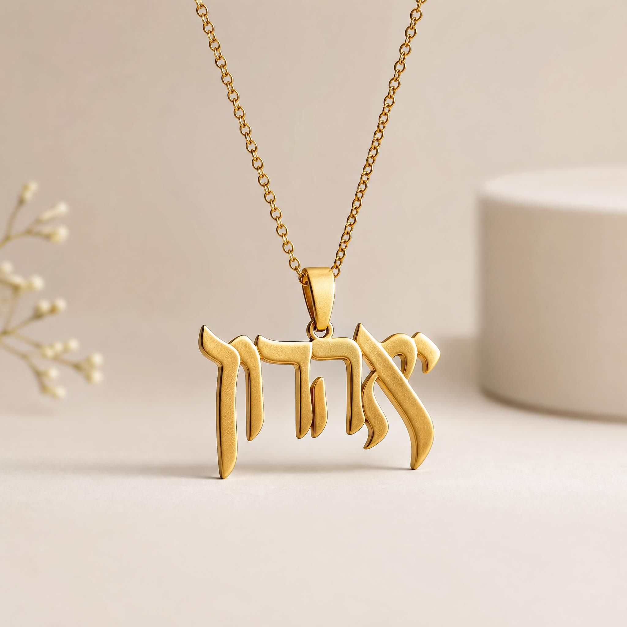 Détail d'un Kalligraphe Aaron Kali en or jaune 18k sur chaîne dorée, lettre hébraïque sculptée à la main, fond épuré