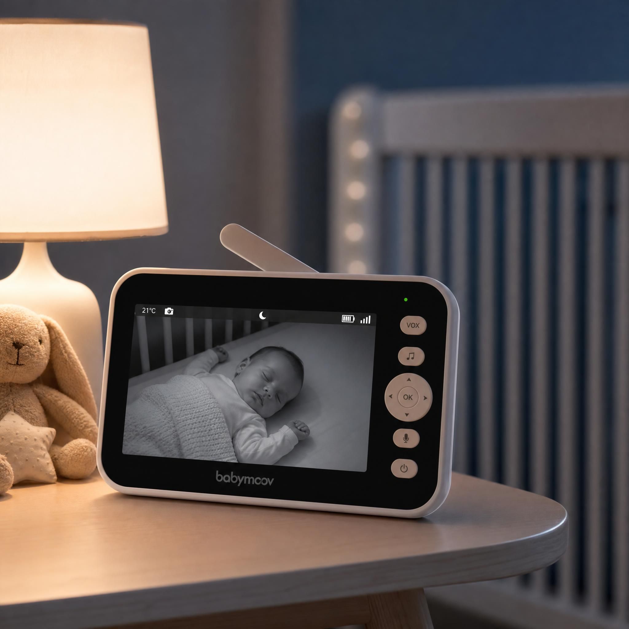 Babyphone vidéo intelligent posé sur une table de chevet, écran affichant un bébé endormi en vision nocturne infrarouge