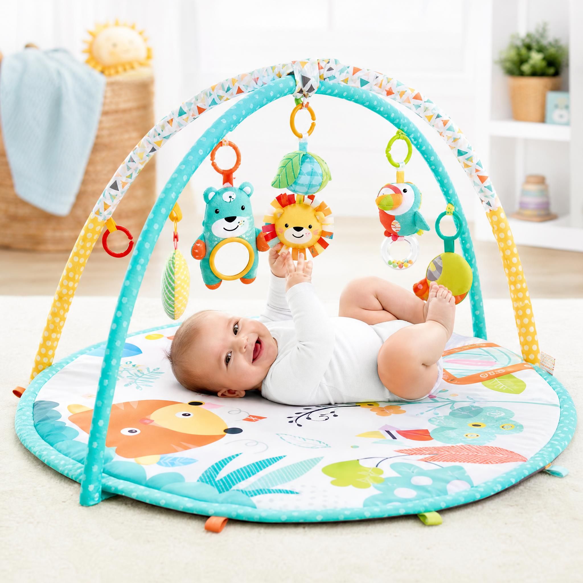 tapis d'éveil coloré avec arches et jouets suspendus, bébé allongé dessus souriant, fond clair et lumineux