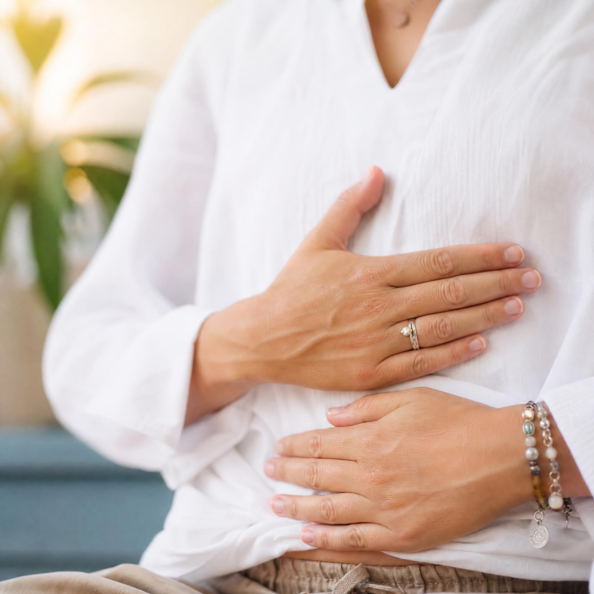 Gros plan sur des mains posées sur le ventre, lumière naturelle douce, ambiance de relaxation et de connexion corps-esprit