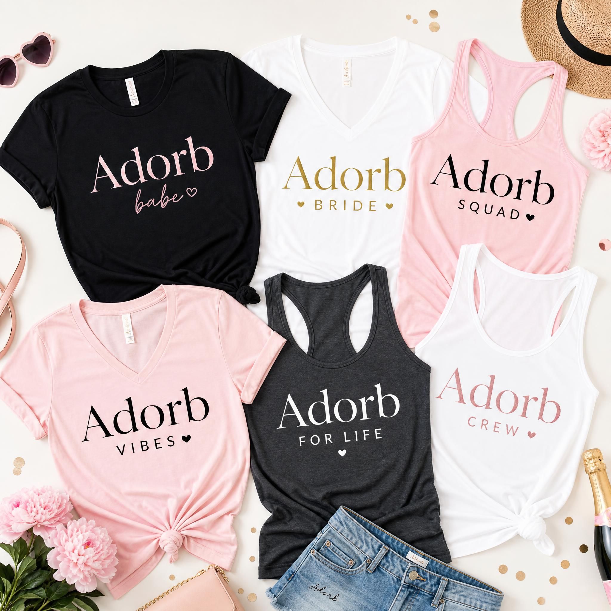 Flat lay of multiple Adorb bachelorette shirt styles including tees, v-necks, and tank tops arranged together