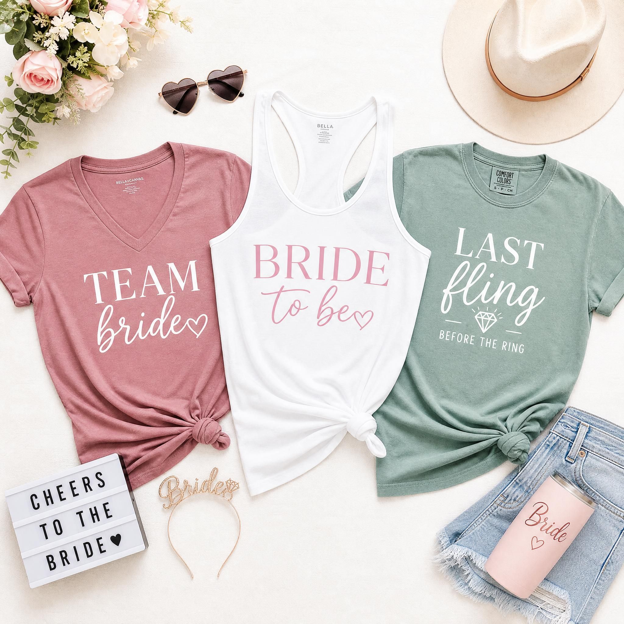 Flat lay of different bachelorette shirt styles including a v-neck, tank top, and Comfort Colors tee in coordinating colors