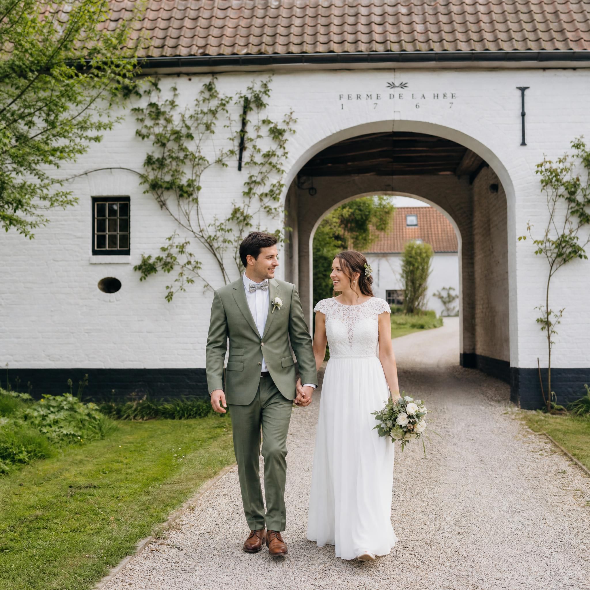 Couple de mariés main dans la main dans une ferme brabançonne à Grez-Doiceau, reportage photo mariage naturel Brabant wallon