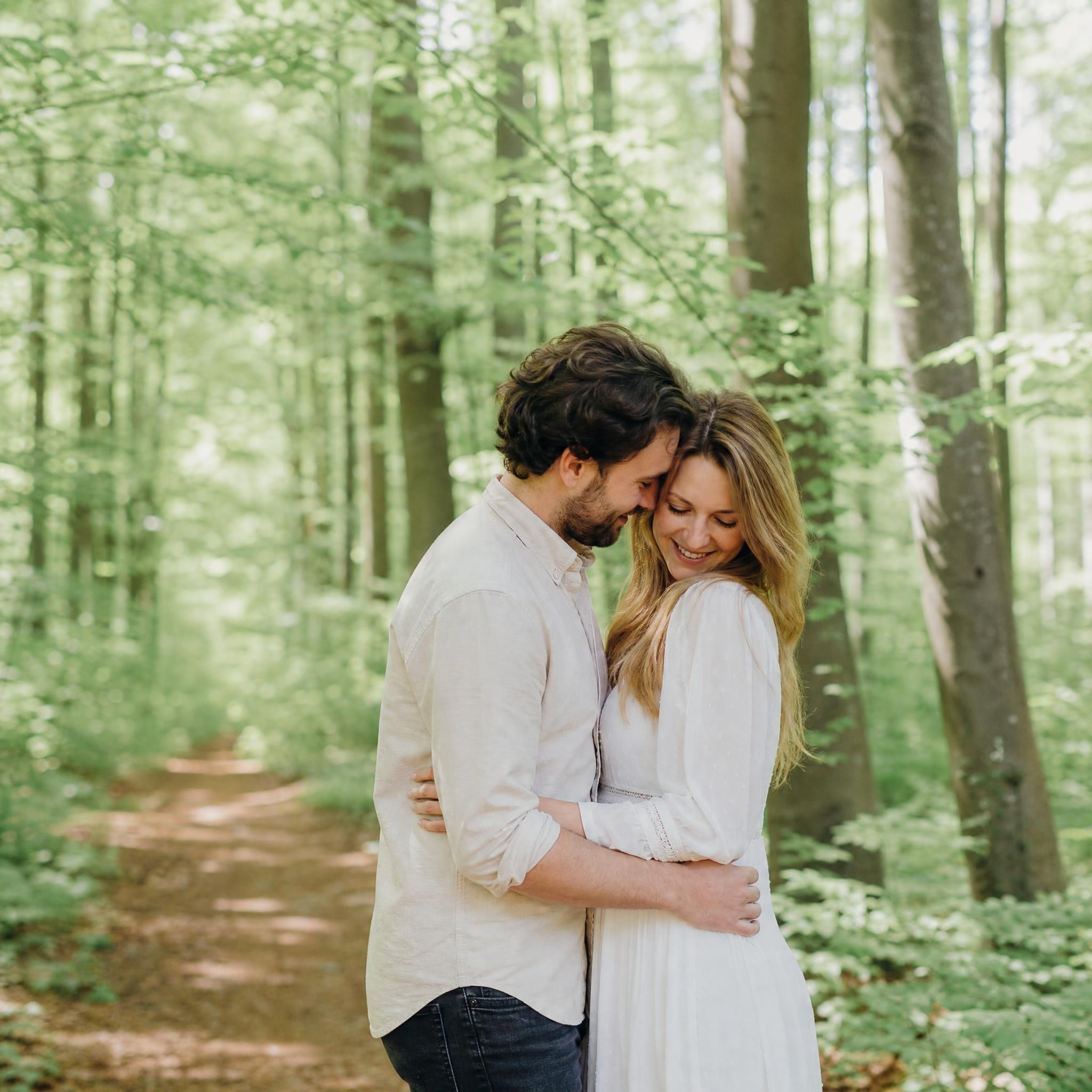 Couple enlacé lors d'un shooting d'engagement naturel dans la Forêt de Soignes près de La Hulpe, photographe mariage naturel Belgique
