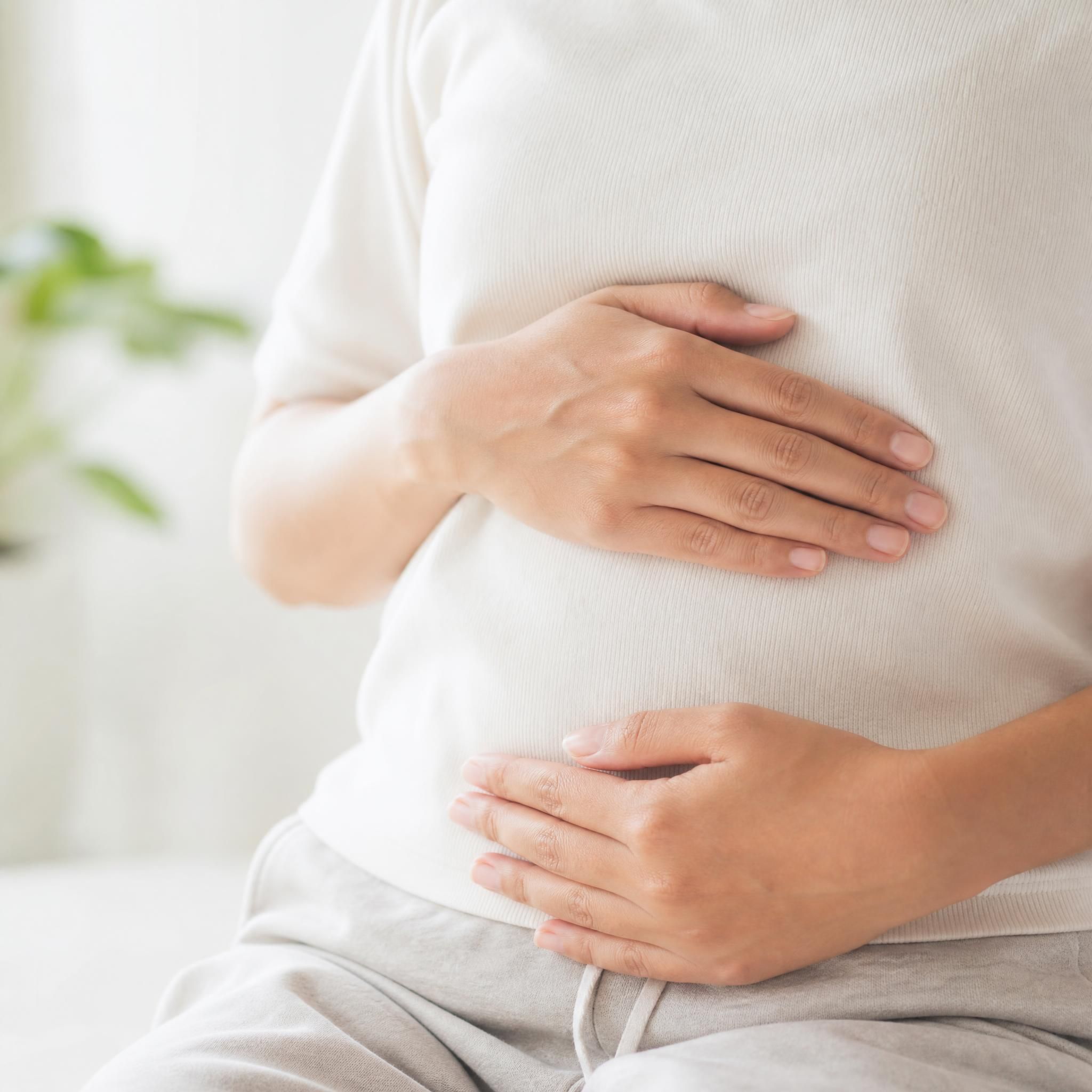 Gros plan sur des mains posées sur le ventre d'une personne en train de pratiquer la respiration abdominale profonde, fond épuré et lumineux, ambiance calme et apaisante