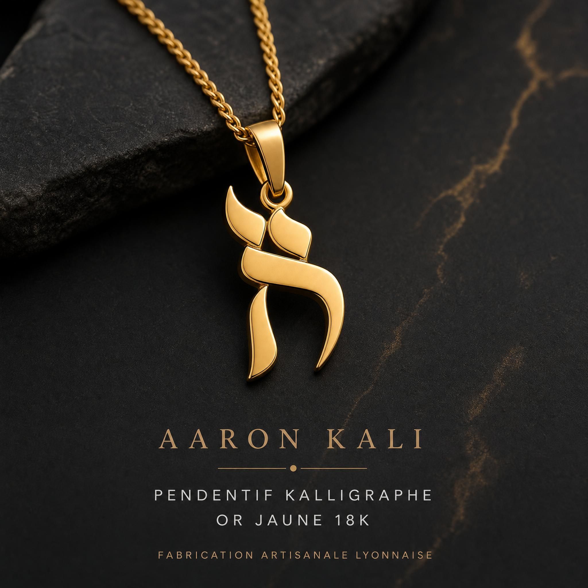 Pendentif Kalligraphe Aaron Kali en or jaune 18k avec lettre hébraïque, bijou artisanal lyonnais posé sur fond sombre et élégant