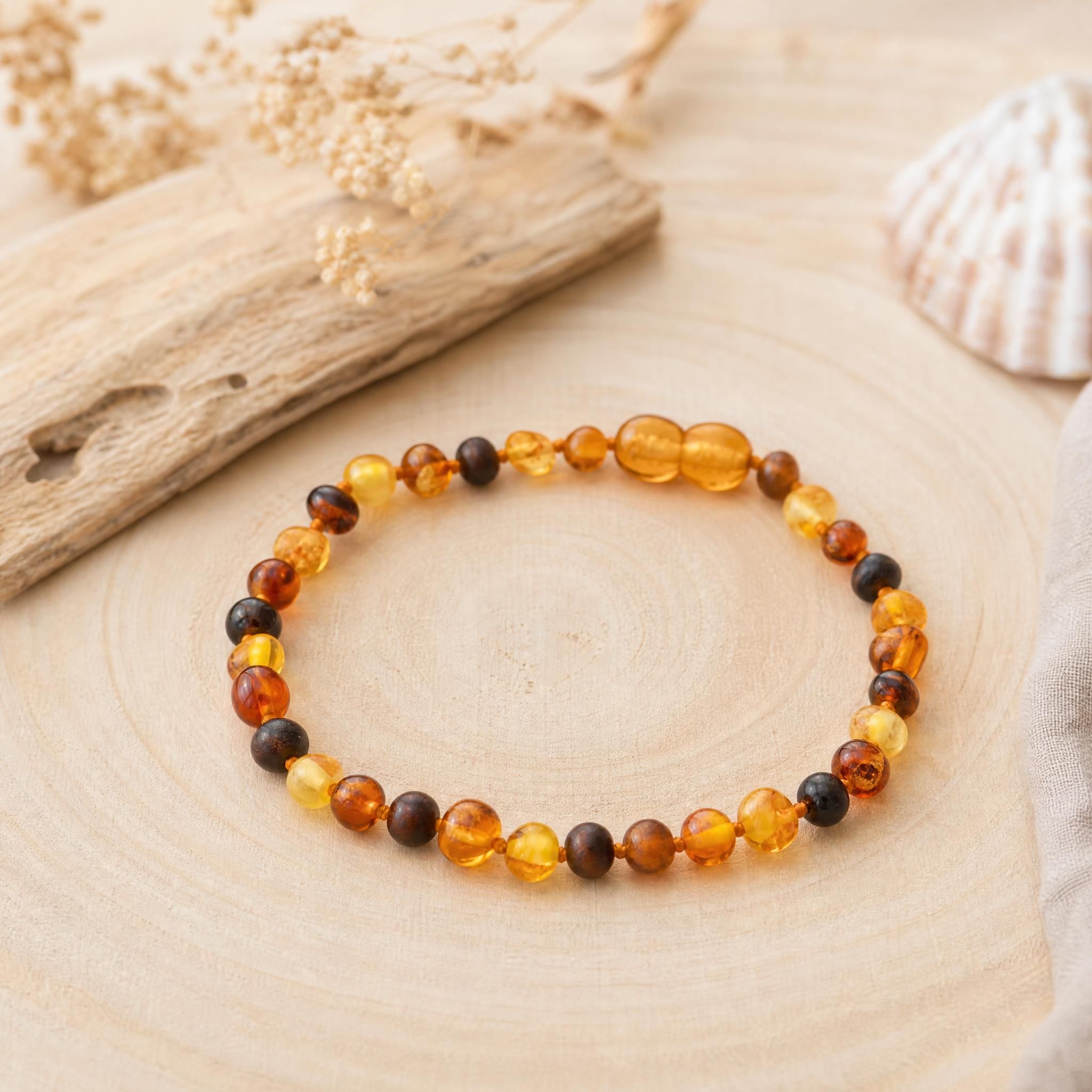 Collier ambre bébé naturel de la mer Baltique posé sur une surface en bois douce, perles d'ambre authentiques
