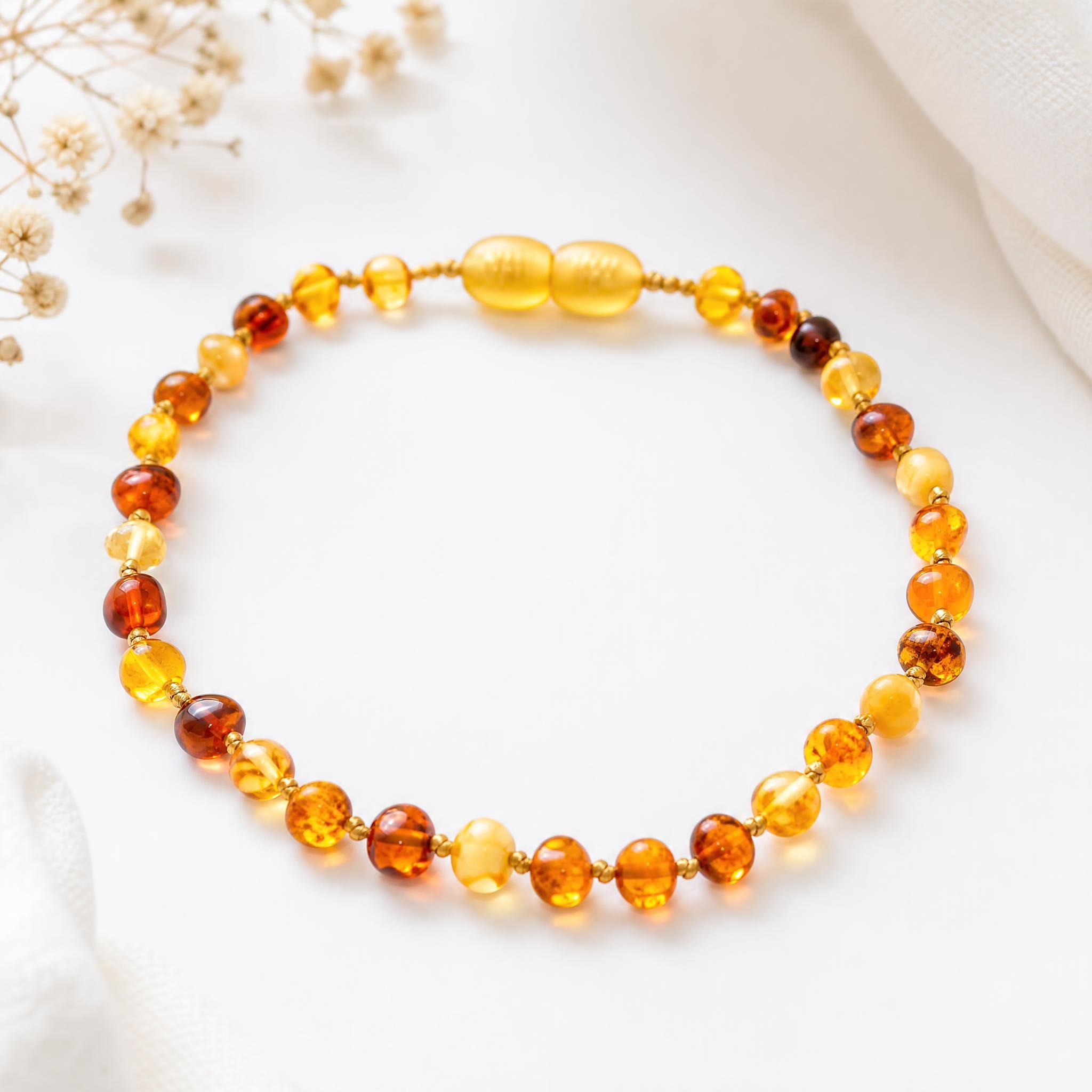 collier ambre bébé naturel mer Baltique perles dorées sur fond blanc doux