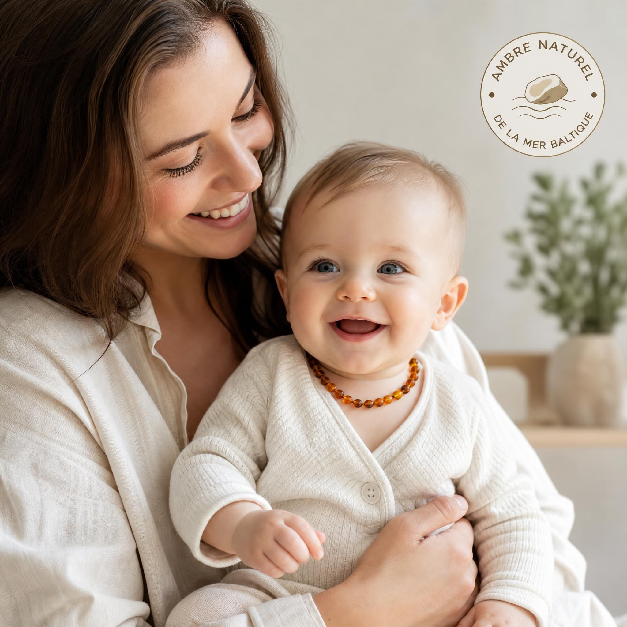 Maman tenant son bébé souriant qui porte un collier d'ambre naturel de la mer Baltique
