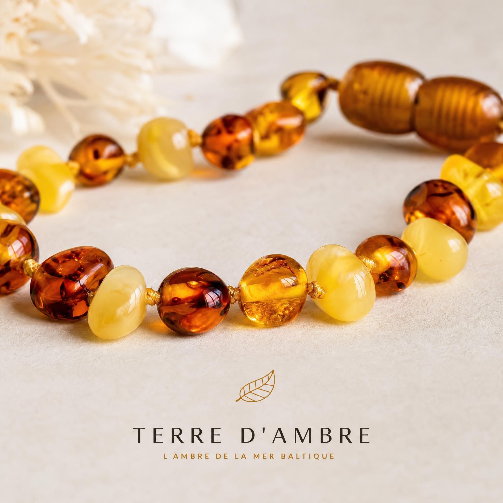 Gros plan sur des perles d'ambre naturel de la mer Baltique aux teintes miel et cognac, collier bébé Terre d'Ambre