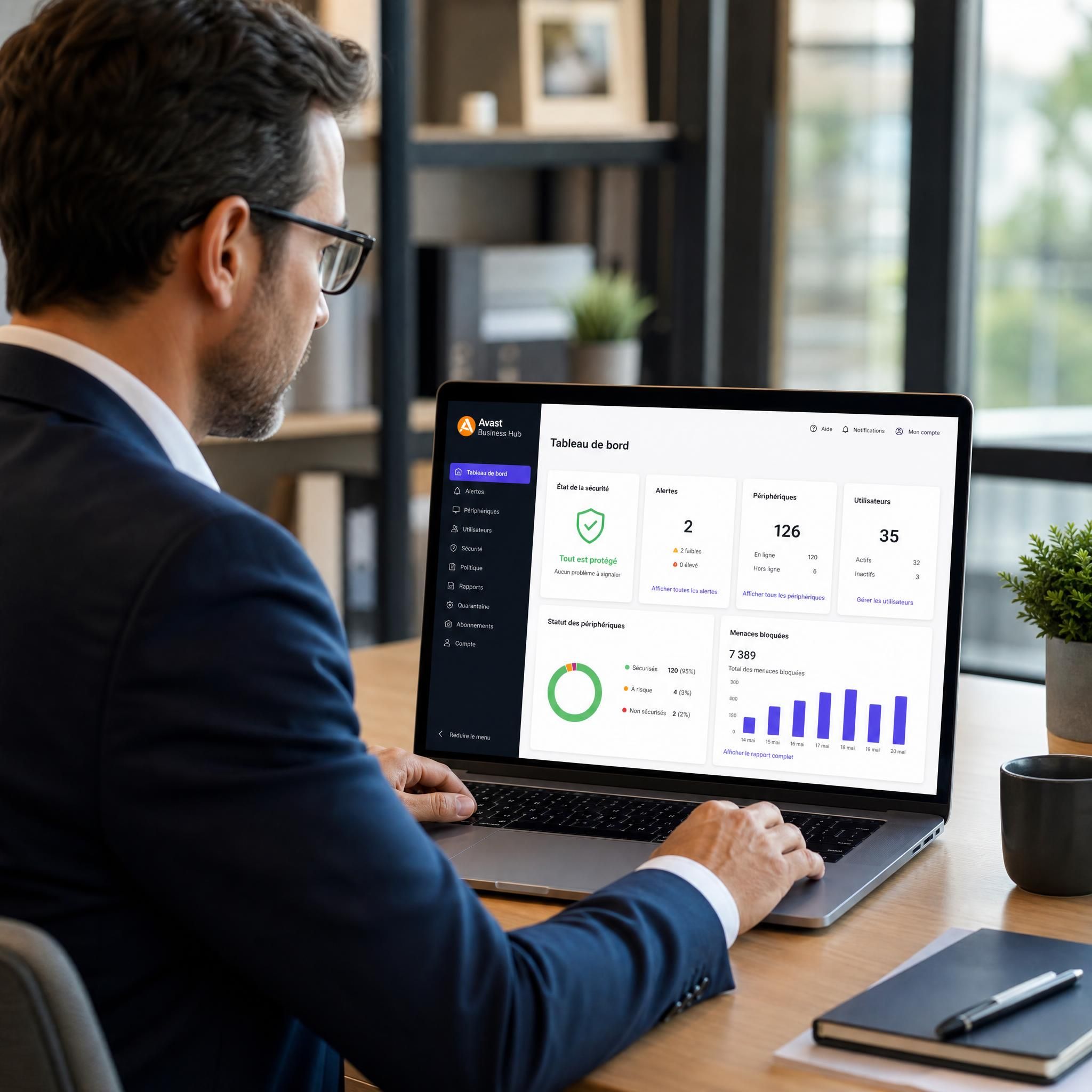 Dirigeant de PME consultant la console de gestion Avast Business Hub sur son ordinateur pour surveiller la sécurité de son parc informatique