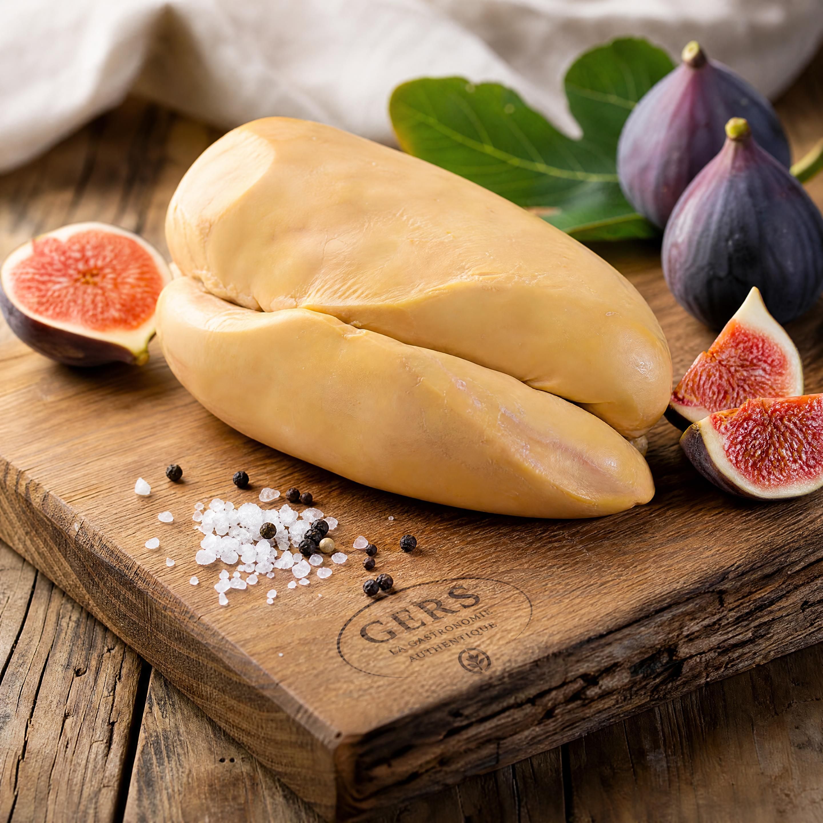 Un foie gras entier de canard du Gers présenté sur une planche en bois rustique avec de la fleur de sel, des grains de poivre noir et des figues fraîches